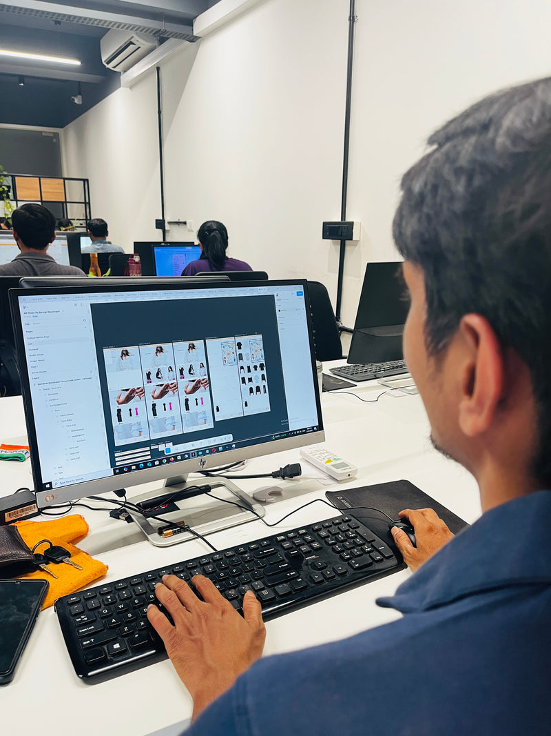 An Ambiw UI/UX designer wireframing a custom e-commerce web layout on a desktop computer.