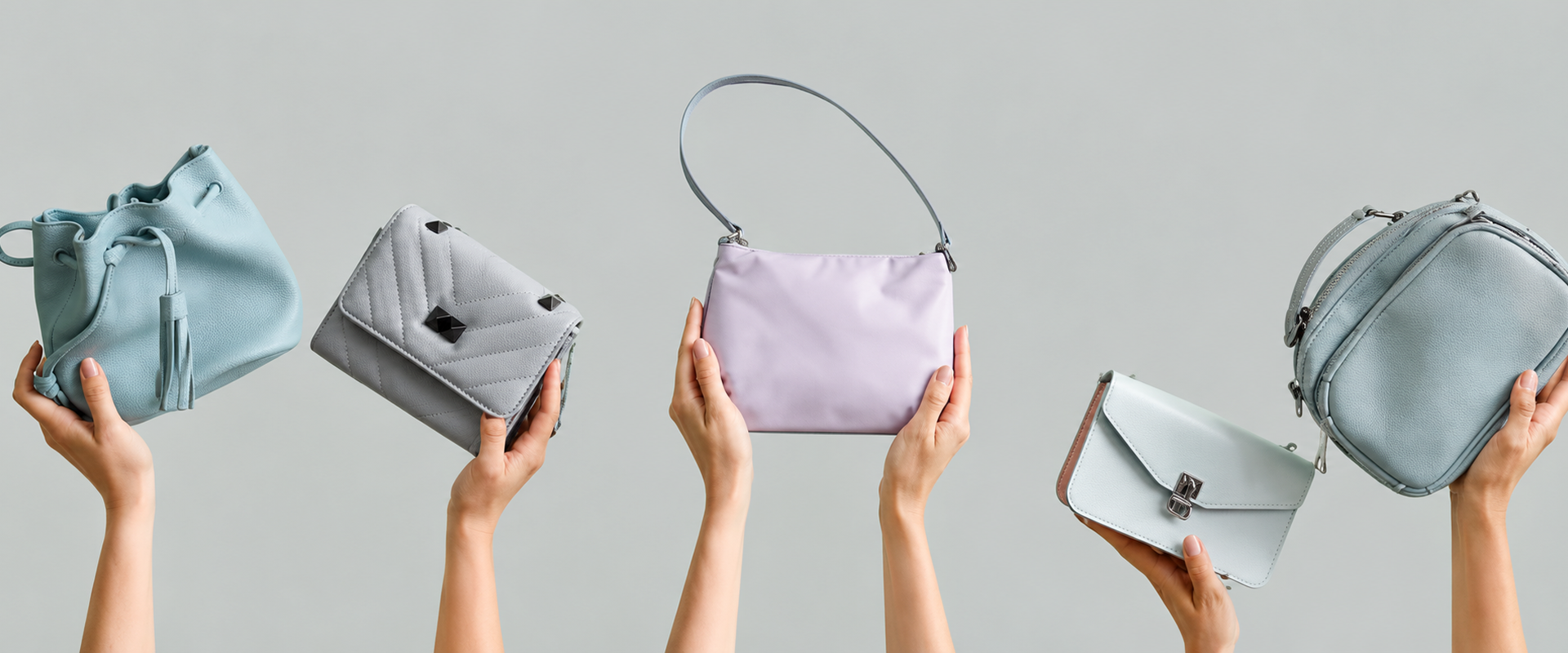 Hands raised against a clean grey background, holding up a stylish lineup of pastel handbags