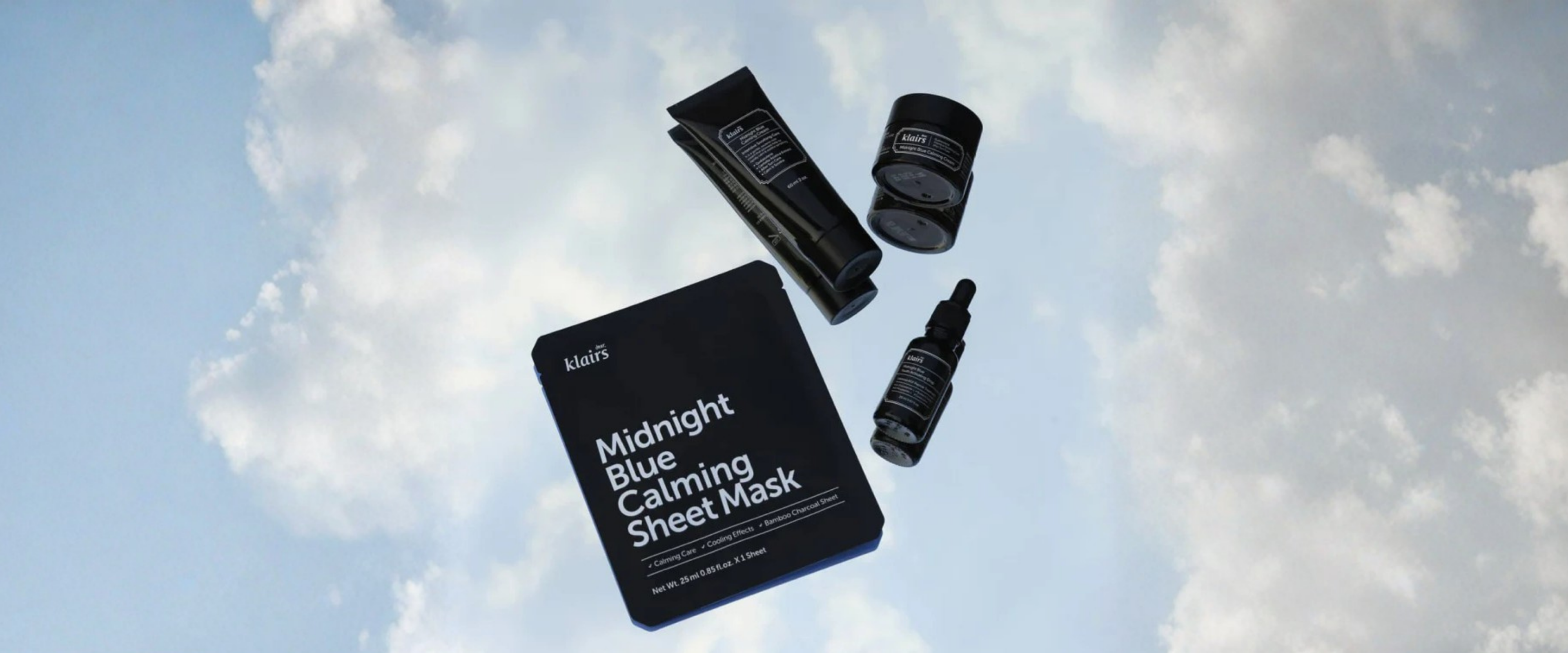 Skincare products including a sheet mask, cream, and serum against a cloudy sky background.