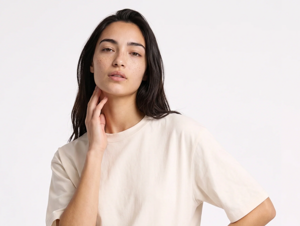 A close-up studio portrait of a woman wearing a cream-colored, relaxed-fit t-shirt of Jerico