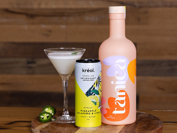 A can of Kréol Pineapple Jalapeño & Lime next to a bottle of Tanica spirit on a wooden board