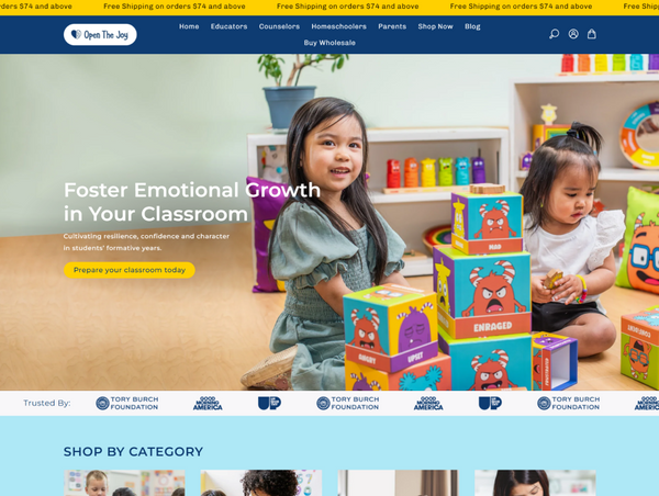 A desktop homepage banner for Open the Joy featuring two young girls playing with colorful monster emotion blocks