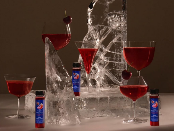 An artistic lifestyle image displaying an elegant assortment of glassware filled with vibrant red cocktails, some garnished with fresh cherries